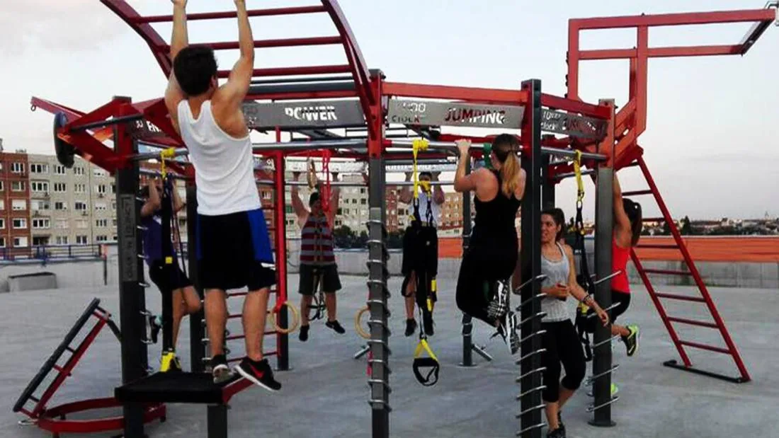 Mehrere Personen trainieren an Klimmzugstangen und Ringen eines Calisthenics-Gestells aus Stahl